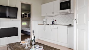 A compact kitchen with white cabinets, a microwave, and a small dining area with a table set for two. - First Camp Hagön Halmstad (Halmstad)