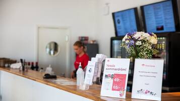 En receptionsdisk med træbordplade, en blomstervase og informationsskilte.