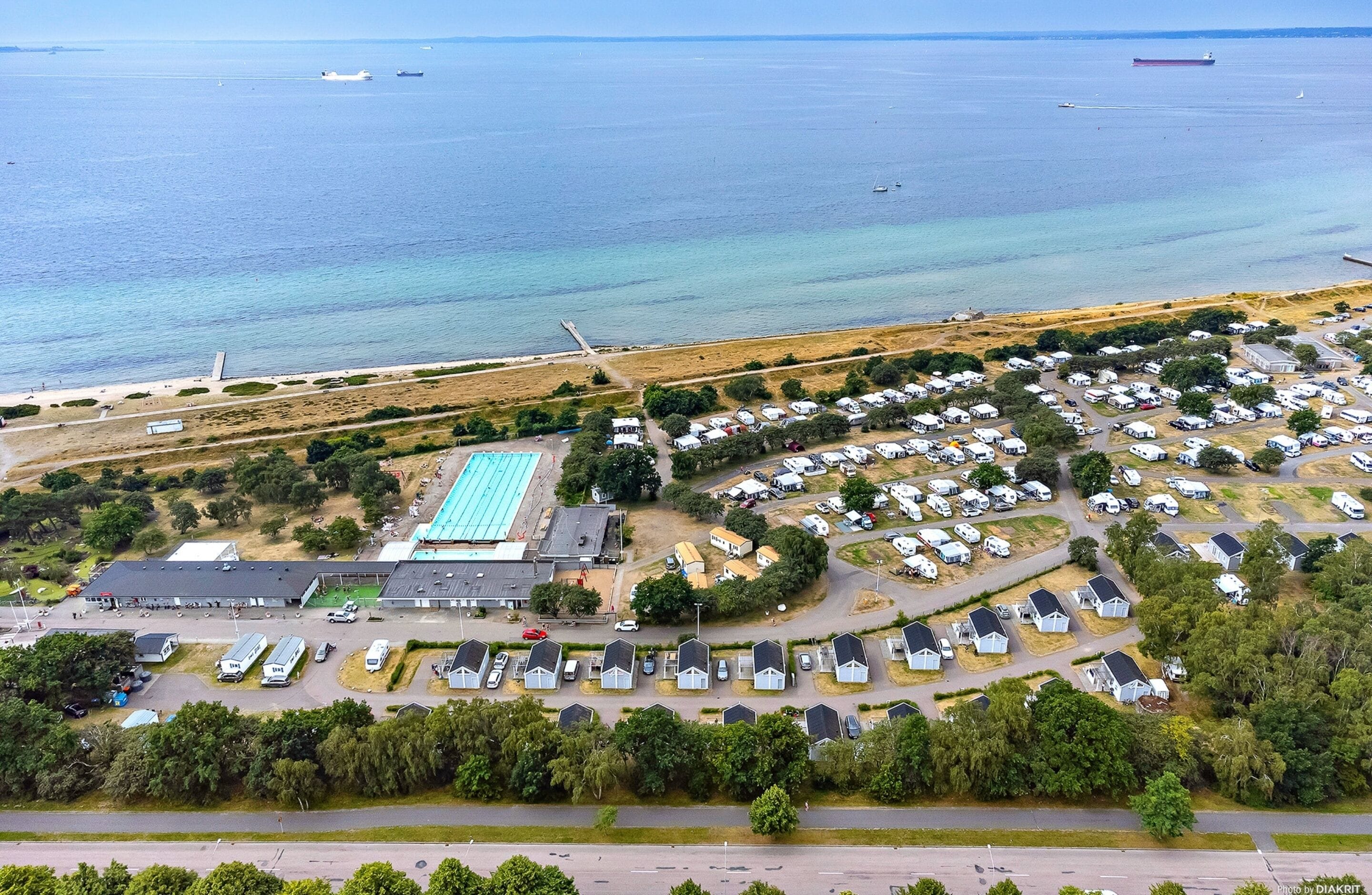 Luchtbeeld van een kustgebied met een jachthaven, een zwembad en een stacaravanhof.