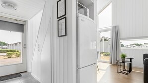 A modern kitchen with white cabinetry, a refrigerator, and a dining area with a table and chairs. - First Camp Råå Vallar Helsingborg (Råå)