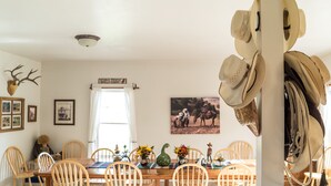 A dining room with a wooden table and chairs, a wall-mounted deer head, framed pictures, and a welcome sign. - Wilson Ranches Retreat (Fossil)