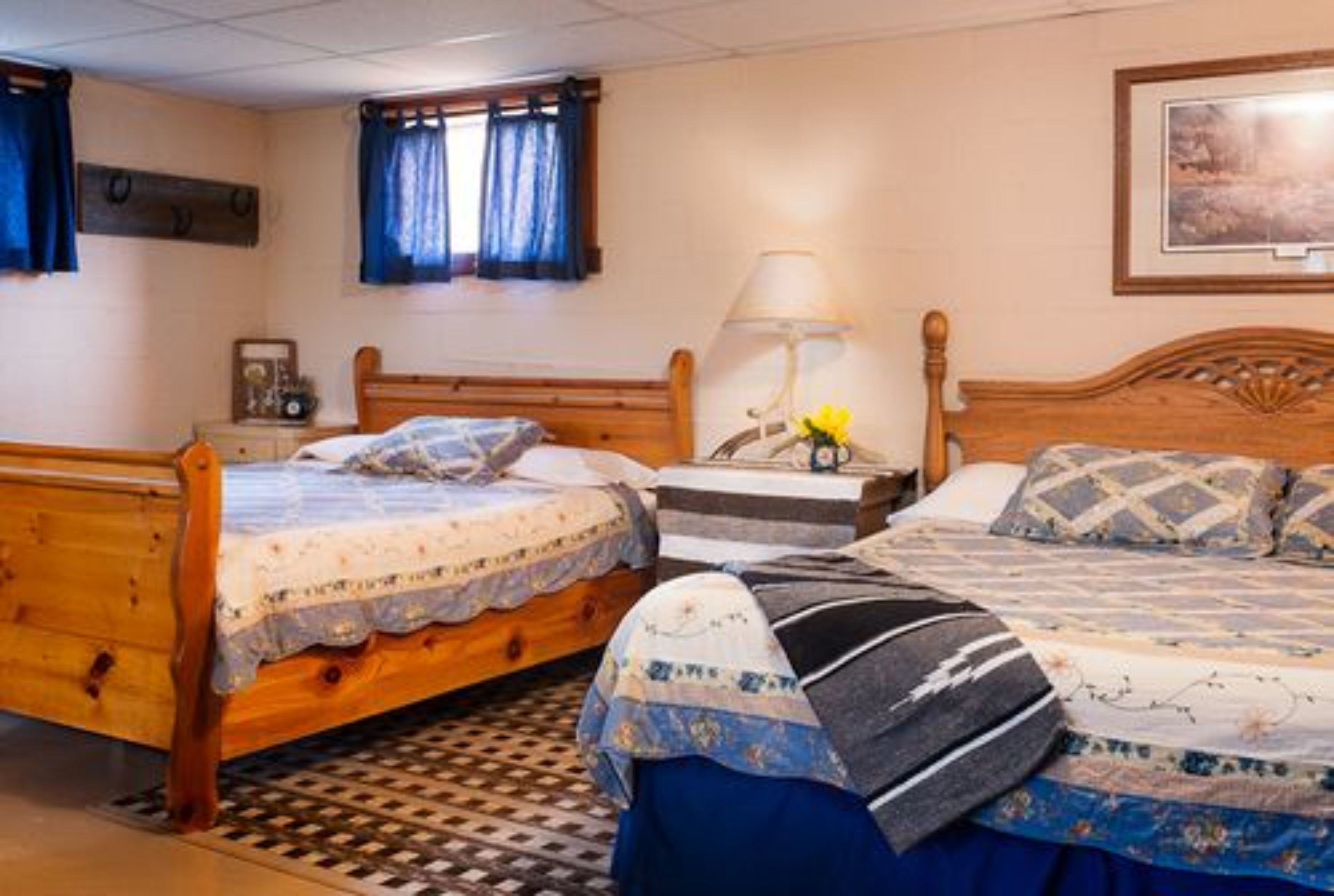 A bedroom with two wooden beds, a nightstand, a lamp, and a framed picture on the wall.