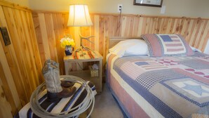A room with a wooden headboard, a bed with a quilt, a nightstand with a lamp, and a decorative item. - Wilson Ranches Retreat (Fossil)