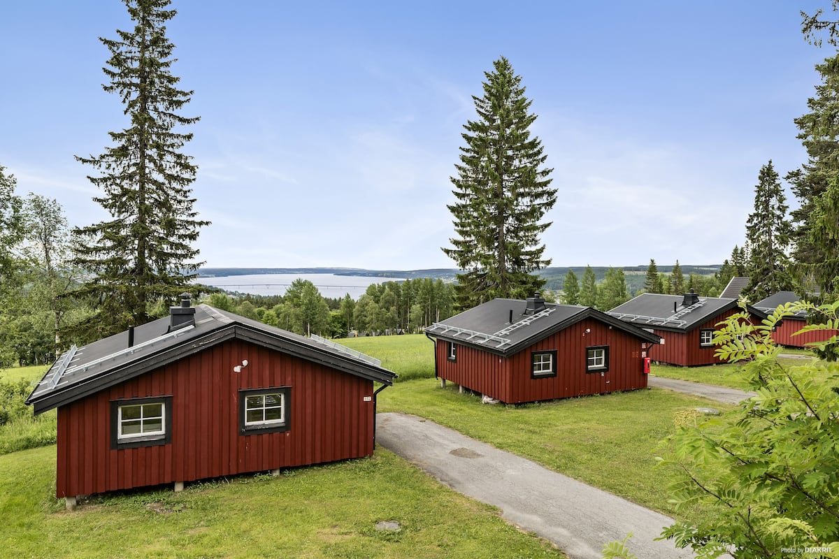A row of red cabins with a clear view of the lake and forest in the background.