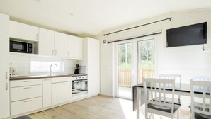 Una cocina moderna con armarios blancos, un microondas, un horno y un comedor con sillas y mesa blancos.