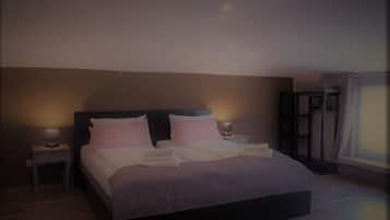 Una cama grande con cabecera, dos mesitas de noche con lámparas y una ventana con cortinas.
