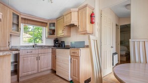 Een compacte keuken met houten kastjes, een koffiezetapparaat en een brandblusser.