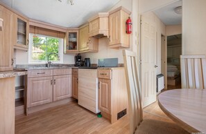 Una cocina compacta con armarios de madera, una cafetera y un extintor.