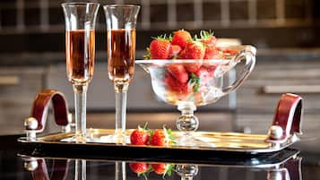Una bandeja con dos vasos de un líquido transparente, un cuenco de fresas y una superficie reflectante.