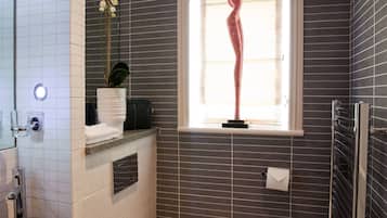 A modern bathroom with a white toilet, a black sink, a window with a decorative plant, and a towel rack.