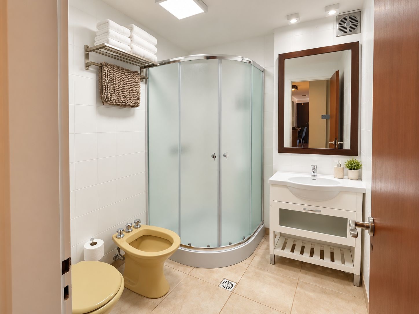 A modern bathroom with a glass shower enclosure, a toilet, and a sink with a mirror above it.