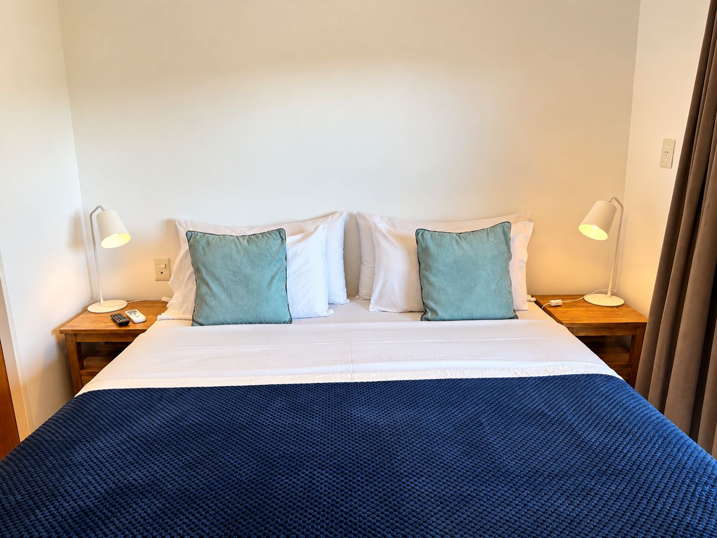 Une chambre d’hôtel comprenant un lit, deux tables de chevet, deux lampes et deux oreillers.