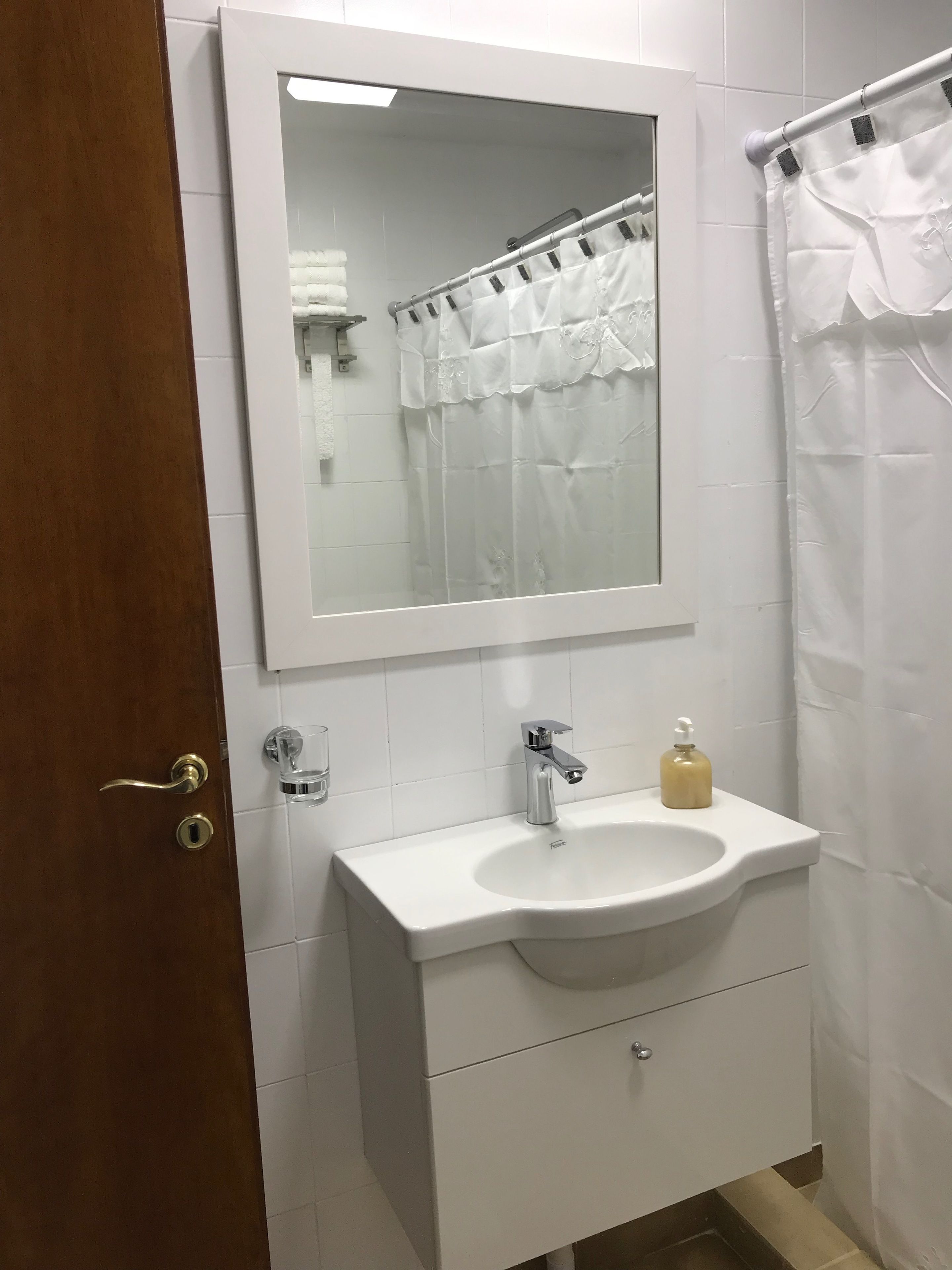 A bathroom with a white sink, a mirror, and a shower curtain.