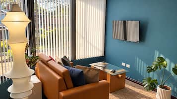 Ein modernes Wohnzimmer mit einer Couch, einem Couchtisch und einem an der Wand befestigten Fernseher.