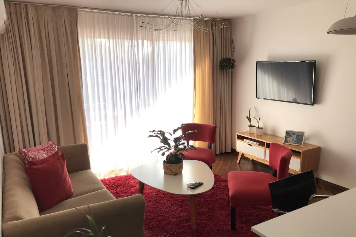 Un salon avec un canapé, des fauteuils, une table basse, un téléviseur et une plante.