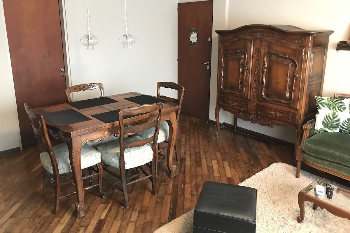 Un coin repas avec une table et des chaises en bois, un buffet et un canapé vert.