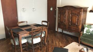 Un comedor con una mesa y sillas de madera, un armario y un sofá verde.