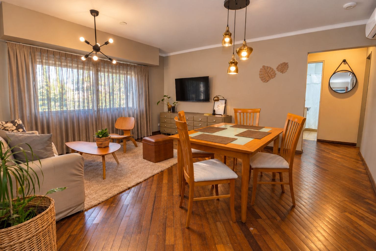 Una sala de estar con una mesa de comedor de madera, sillas, un sofá, un televisor y una chimenea.
