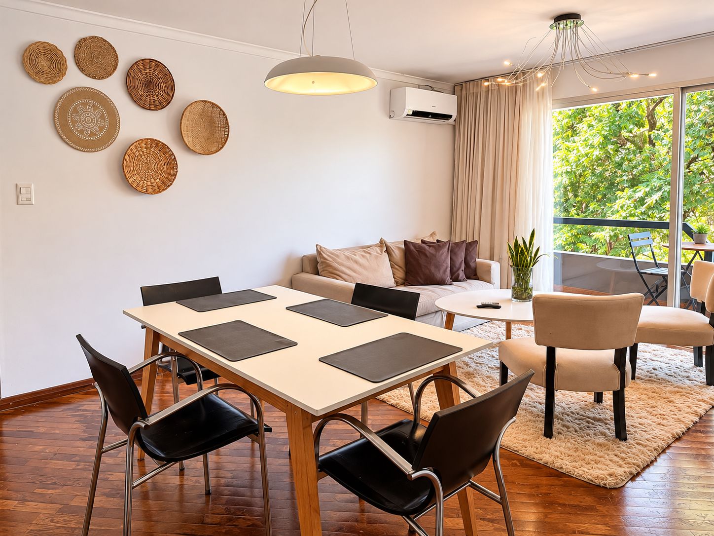 Un salon moderne comprenant un coin repas, un canapé, une table basse et une vue sur la verdure à l’extérieur.