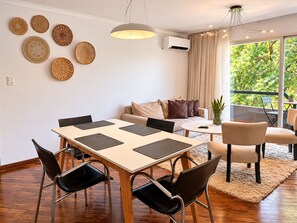 Una sala de estar moderna con comedor, sofá, mesa de centro y vistas a zonas verdes.