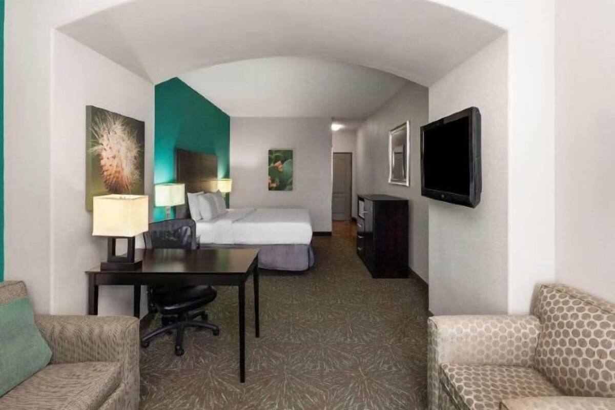 Habitación de hotel con cama, escritorio, silla, televisor y obras de arte.
