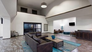 A spacious living area with a sectional sofa, a coffee table, and a TV mounted on the wall.