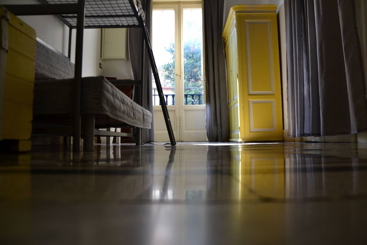 A room with a bunk bed, a yellow cabinet, and a door leading to a balcony.