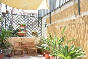 A patio with wooden furniture, potted plants, and a bamboo wall. - Il Lapino (Palermo)