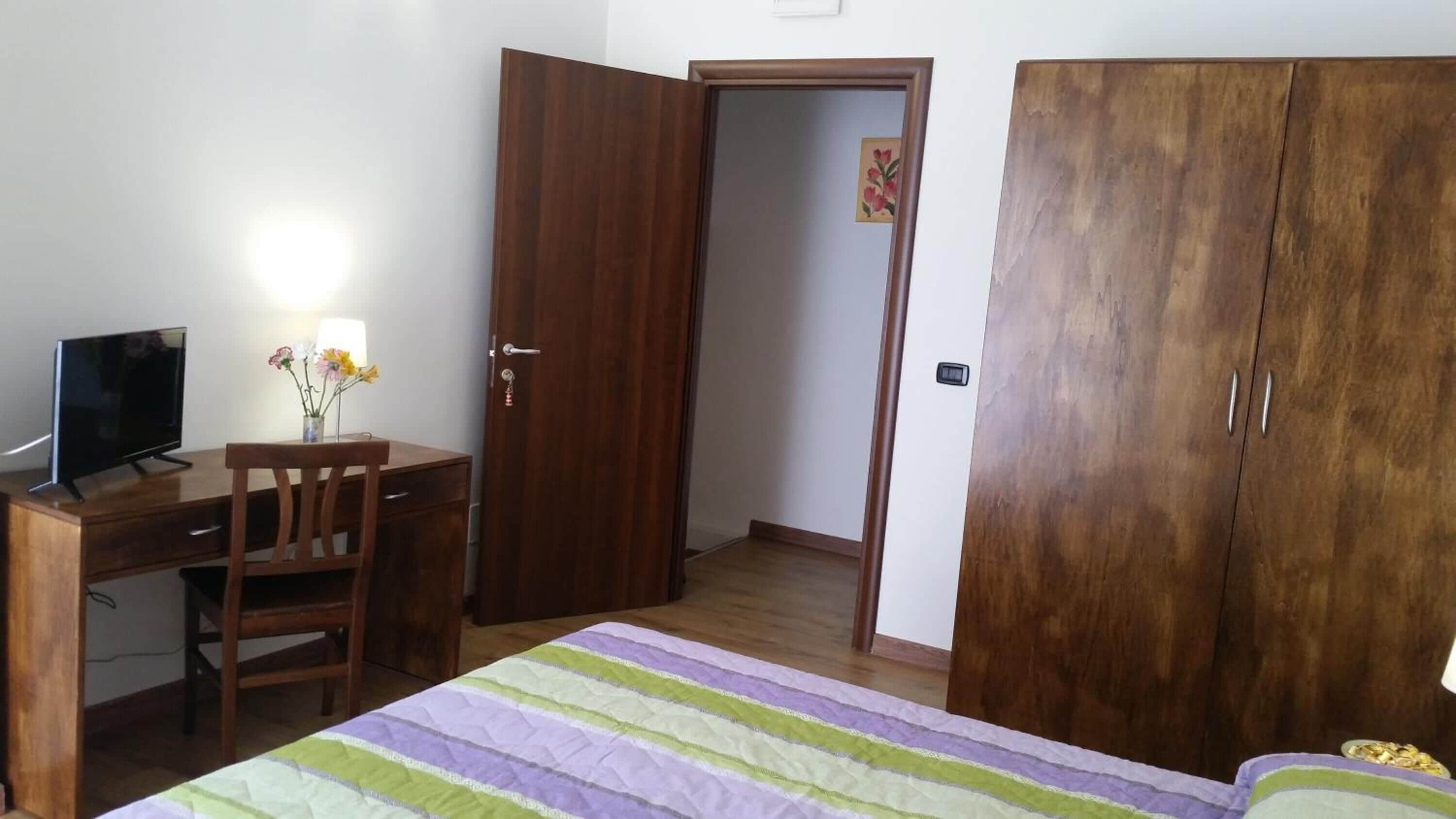 Une chambre à coucher comprenant un lit, un bureau avec une chaise, une télévision et une armoire.
