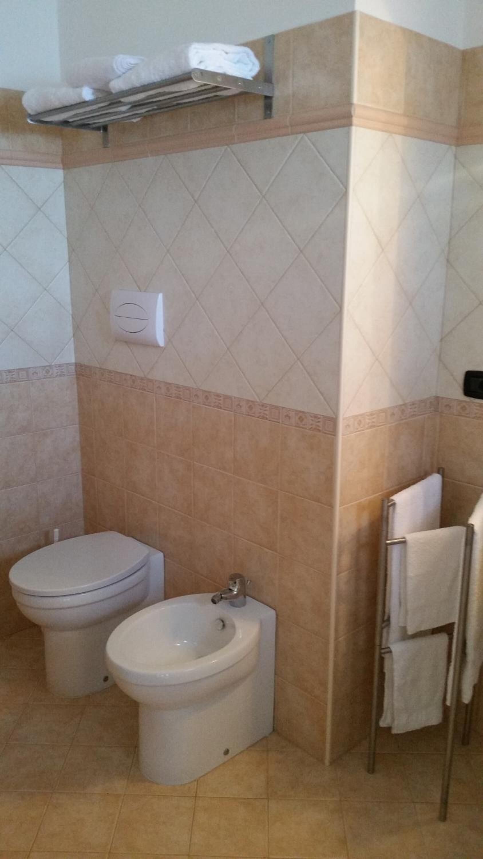 Un baño con inodoro, bidé y toallero.