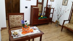 A wooden dining table with a floral tablecloth, a vase with flowers, and a basket of chocolates. - B&B Il Borgo (Scilla)
