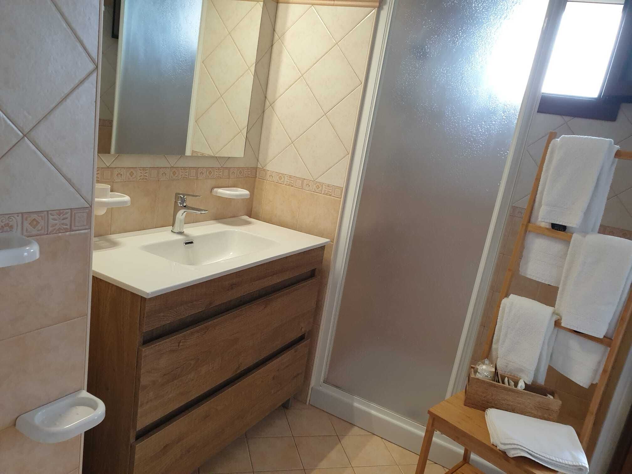 A bathroom with a sink, mirror, wooden vanity, and a towel rack.