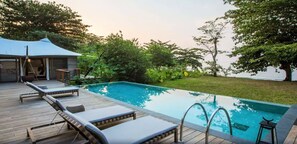 A swimming pool with lounge chairs and a covered area. - Sundy Praia – Principe Collection (Príncipe Island)