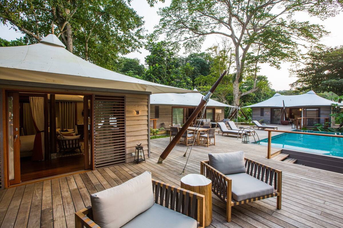 Um deck de madeira com móveis de exterior, piscina e área coberta para relaxar.
