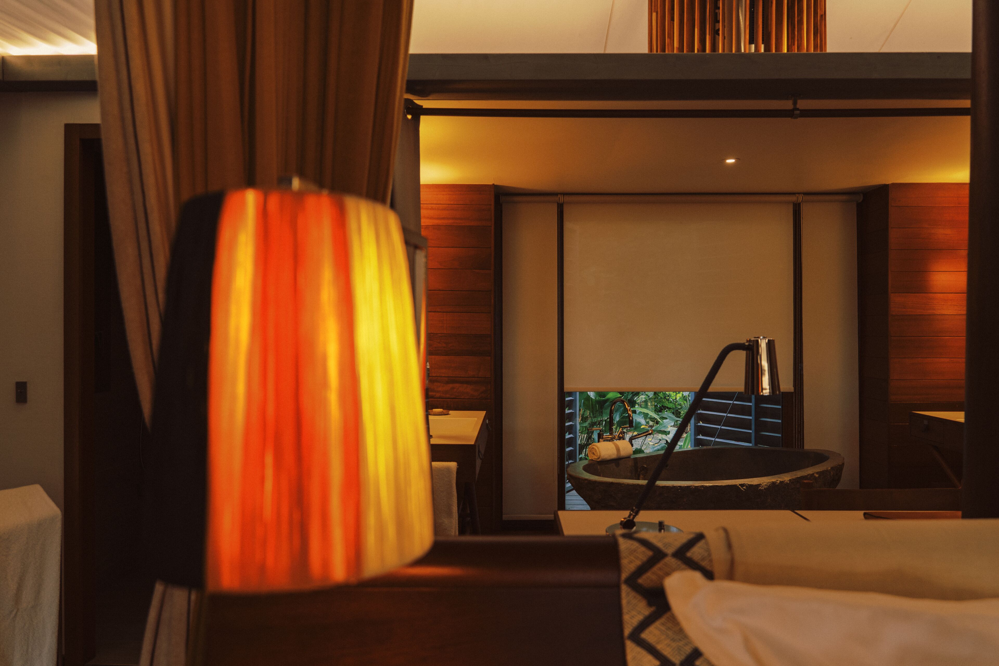 Hotelkamer met een bed, een bureau, een stoel, een lamp en uitzicht op een zwembad.