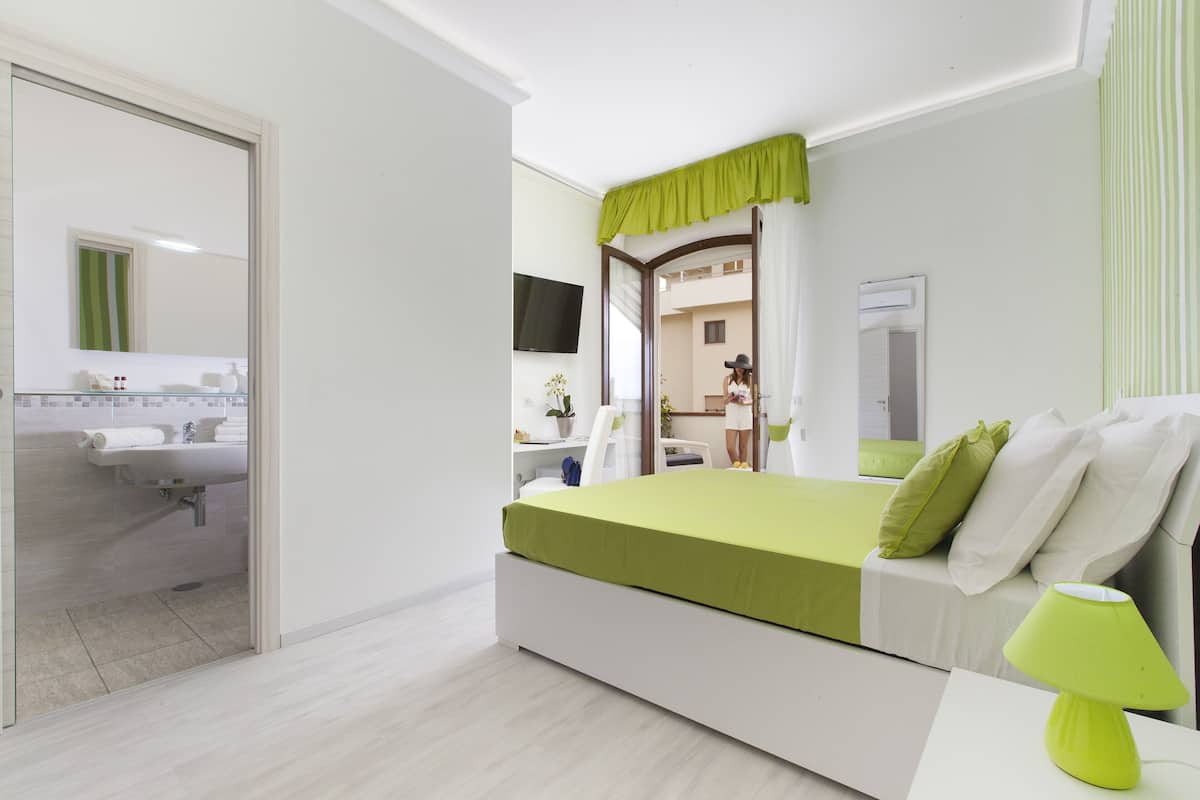 Un dormitorio moderno con cama, mesita de noche y espejo.