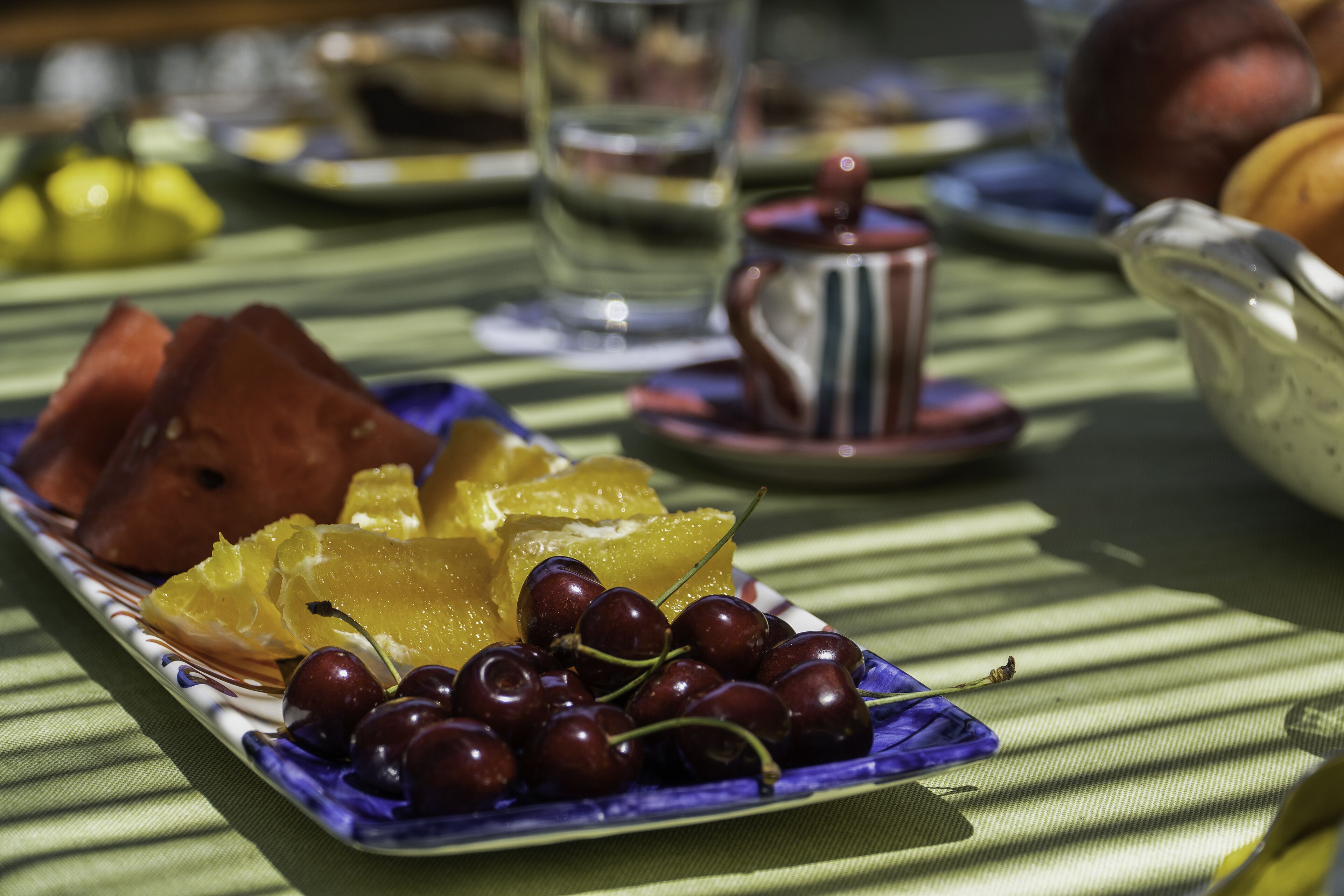 A table with a plate of fruit and a teapot.