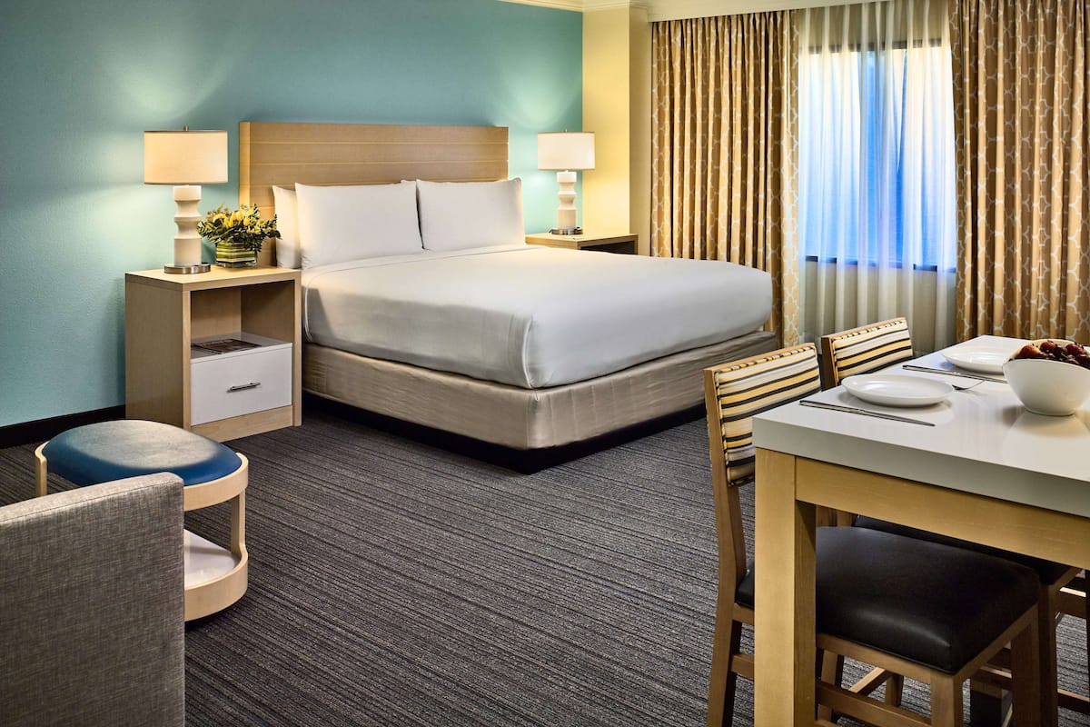 A hotel room with a bed, bedside tables, a desk, and a chair.