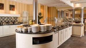 A buffet area with a central serving station, multiple serving lines, and a variety of dishes and utensils. - Sonesta ES Suites Gwinnett Place Atlanta (Duluth)