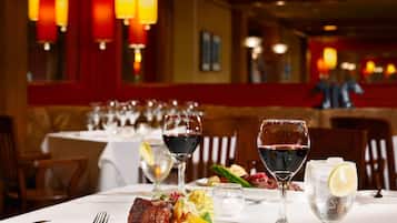 A restaurant table set with a steak, vegetables, and wine glasses.