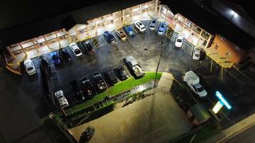 Vista aérea de un estacionamiento con varios autos y algunos camiones, rodeado de edificios con balcones.