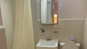 Un baño con bañera, inodoro, lavabo y un espejo sobre el lavabo.
