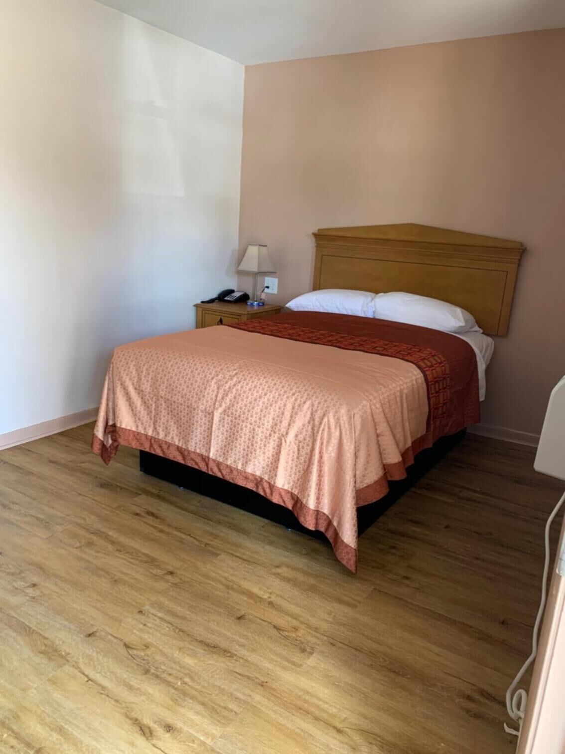 Une chambre à coucher avec un lit en bois, une table de chevet avec une lampe et une chaise blanche.