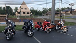 Tres motocicletas estacionadas en un estacionamiento con un edificio al fondo.