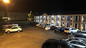 Un parking avec plusieurs voitures et, au fond, le bâtiment d’un motel.
