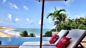 A poolside lounge with two sunbeds and a beach view.