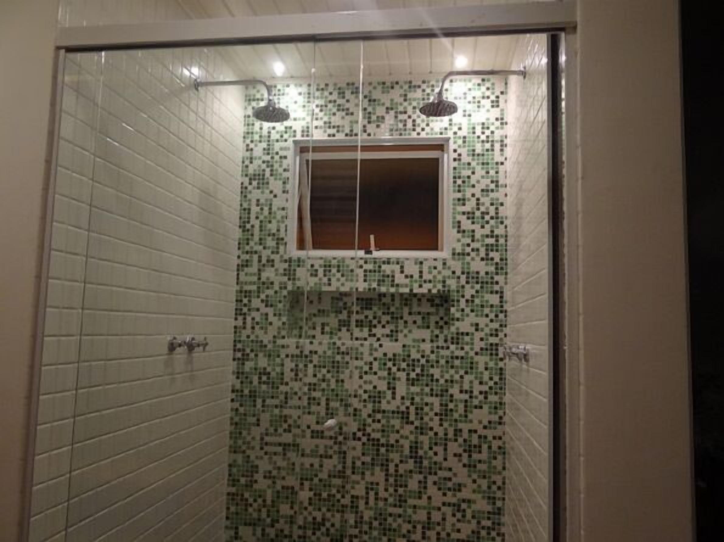 Dutxa amb rajoles de mosaic i una finestra sobre el lavabo.