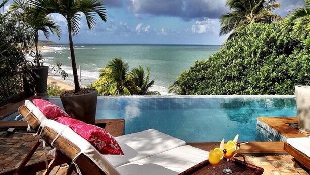 A poolside area with a view of the ocean, a lounge chair, and a tray with drinks. - Pousada Sagi Iti (Baia Formosa)