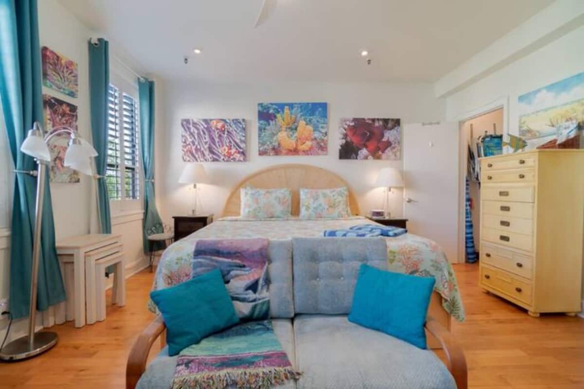 Ein Schlafzimmer mit einem großen Bett, zwei Nachttischen, einer Kommode und Kunstwerken an den Wänden.