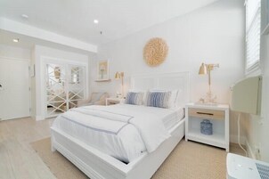 Un dormitorio moderno con una cama grande, paredes blancas y un adorno en la pared.